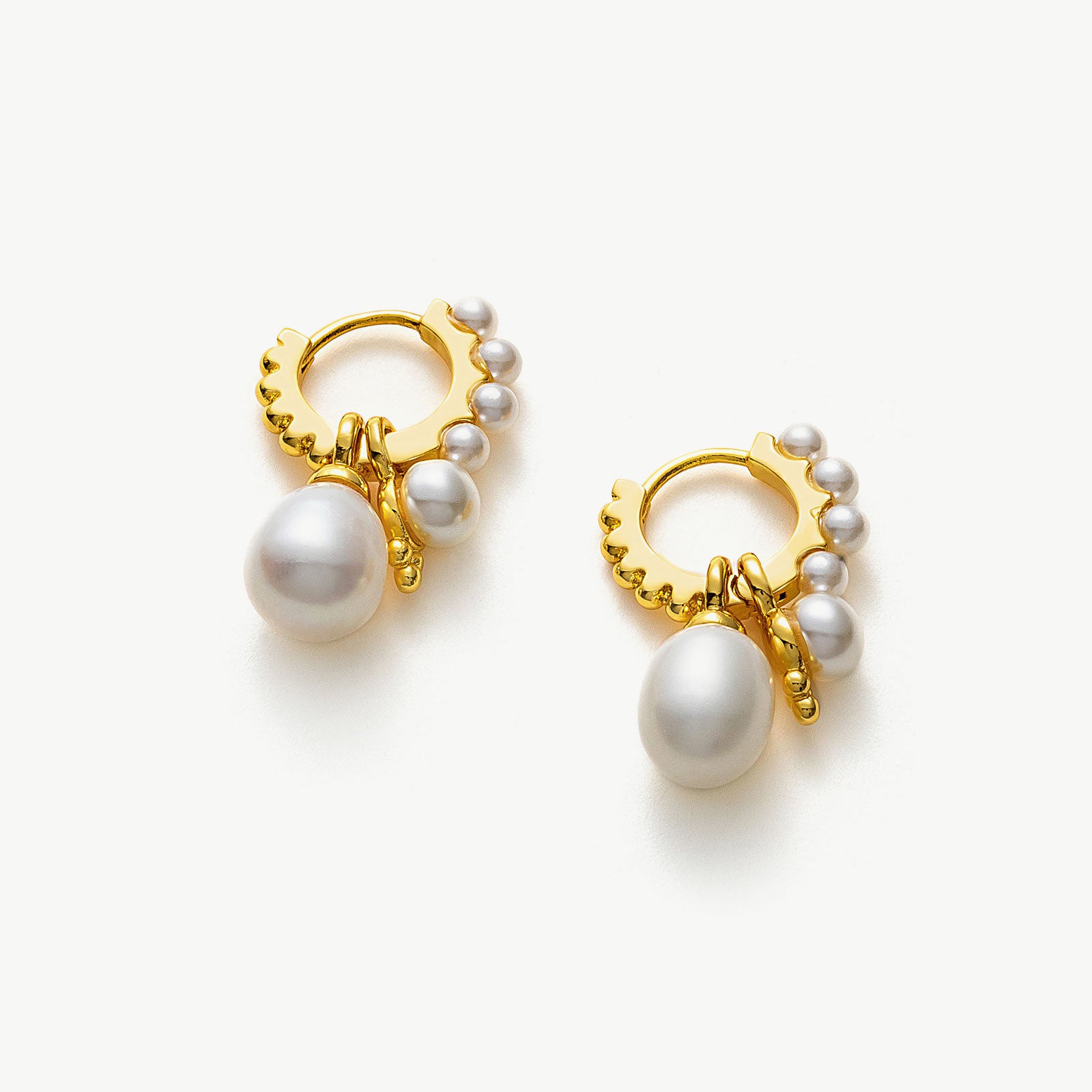 Pearl Huggie Hoops in Gold, a luxurious and gilded accessory that embraces your ears with the timeless elegance of pearls and the warmth of golden tones