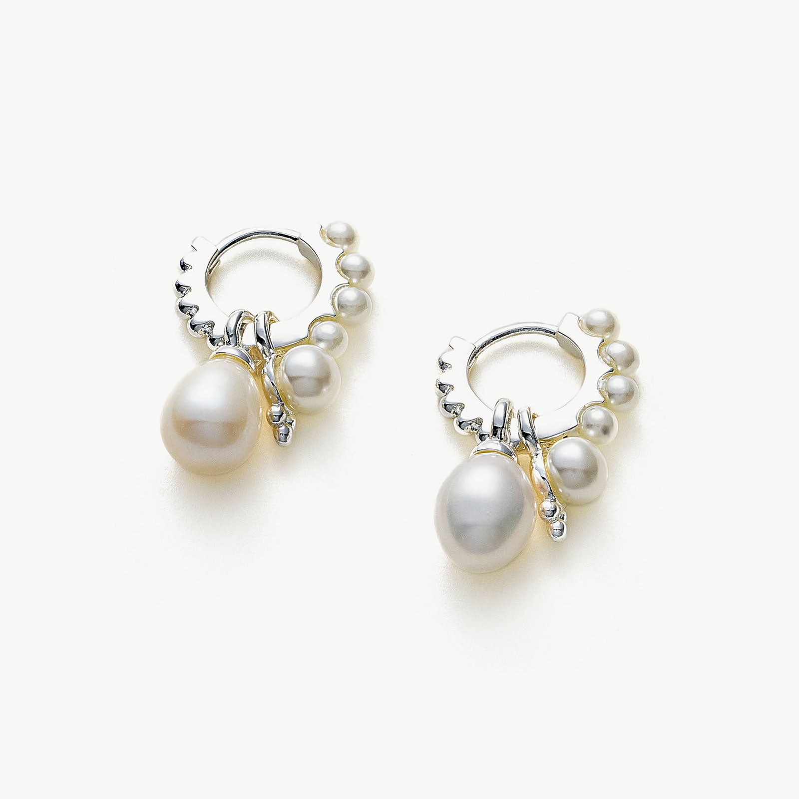 Pearl Huggie Hoops in Silver, a sleek and stylish accessory that embraces your ears with the timeless elegance of pearls against a silver backdrop