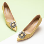 Elevate your style with these yellow embellished pumps adorned with sparkling crystals and a modern buckle, offering striking elegance and a bold fashion statement.