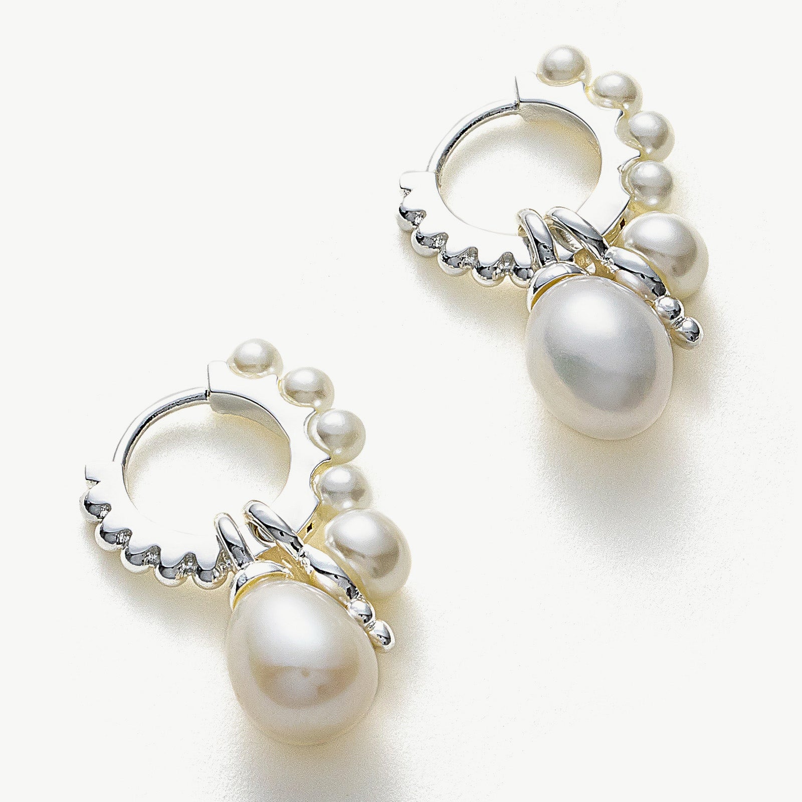 Silver Pearl Huggie Hoops, featuring a lustrous display of pearls against a silver canvas, adding a touch of sophistication and modern charm to your ear ensemble