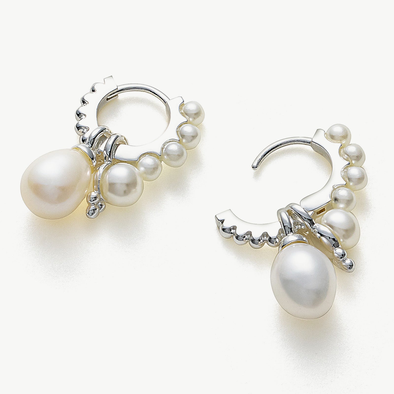 Pearl Huggie Hoops in a moonlit silver hue, delicately adorned with pearls to bring a subtle and enchanting glow to your ears