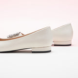 Step into sophistication with these white flats featuring a crystal buckle, perfect for a polished and refined look.