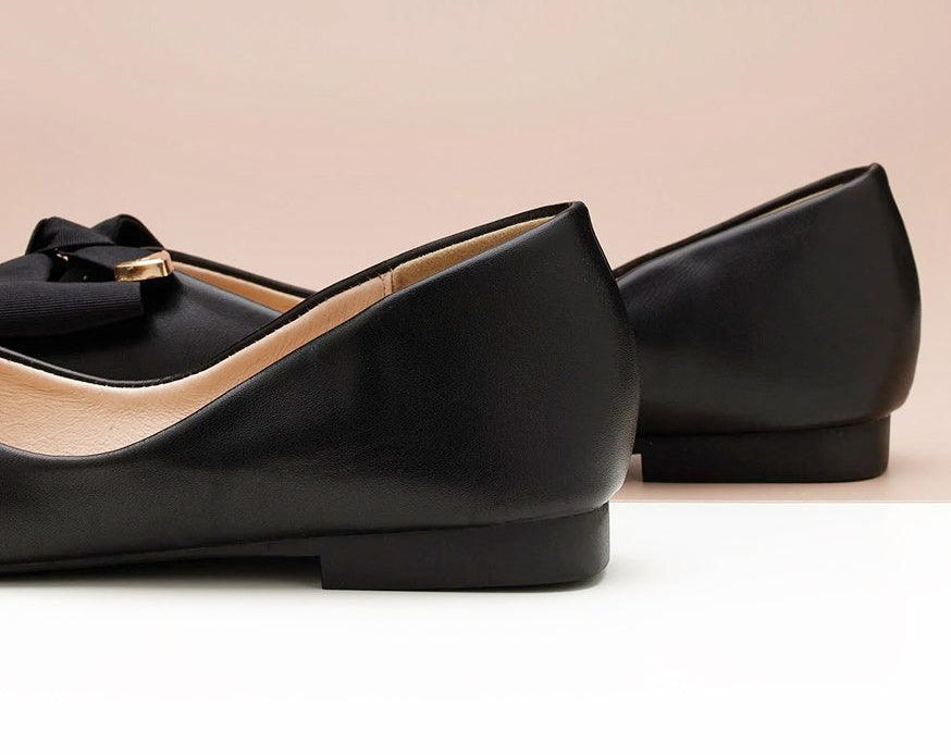 Elegant women's footwear in black with a metal bowknot accent.
