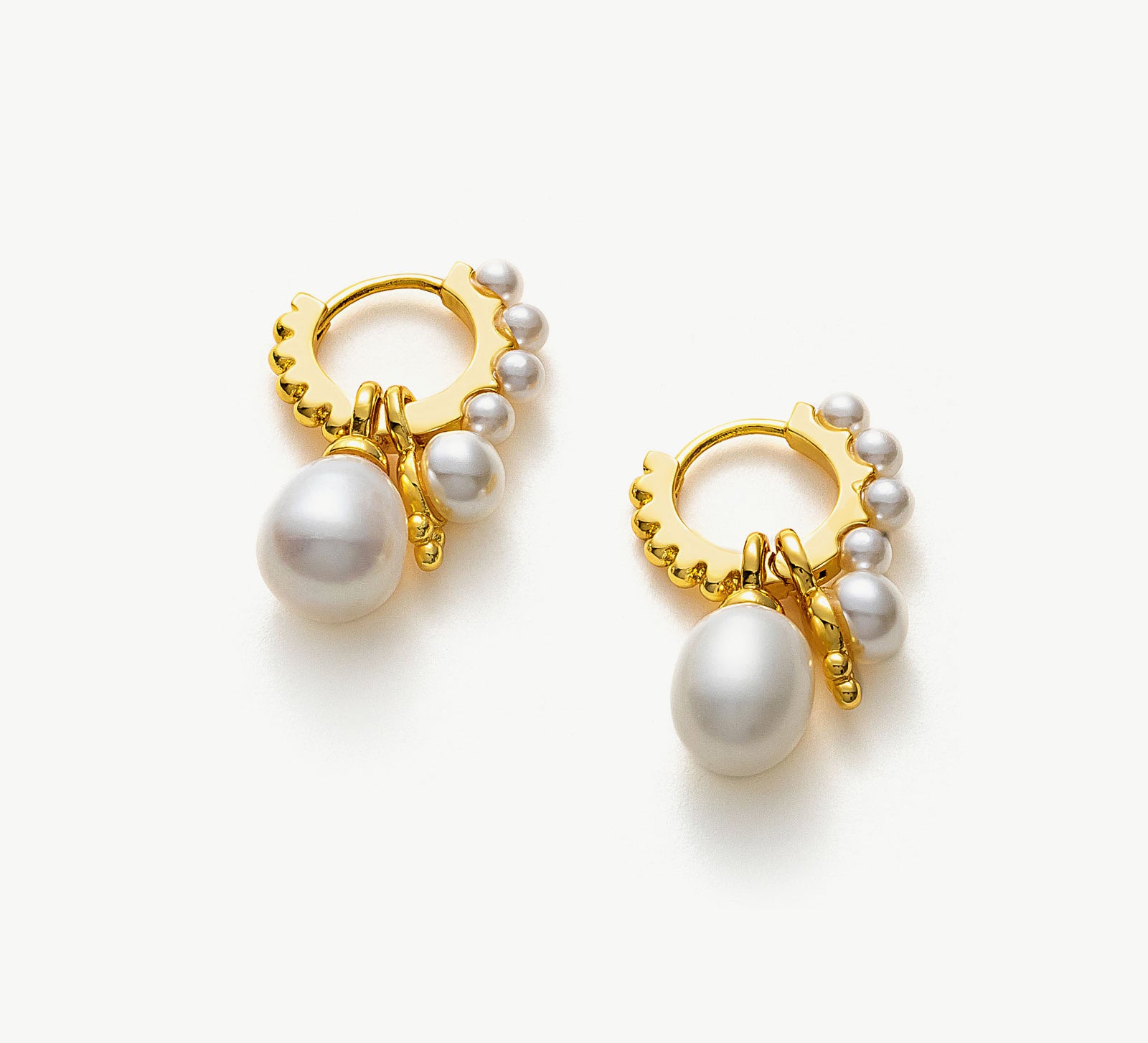 Pearl Huggie Hoops in Gold, a luxurious and gilded accessory that embraces your ears with the timeless elegance of pearls and the warmth of golden tones