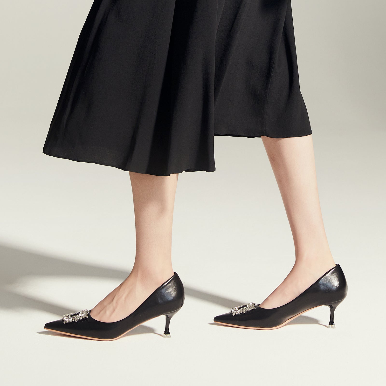 Embrace classic and versatile style with these black pumps, featuring sparkling crystal details and a chic buckle for a timeless look
