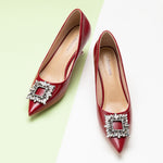 Red leather pumps featuring a dazzling crystal buckle detail.