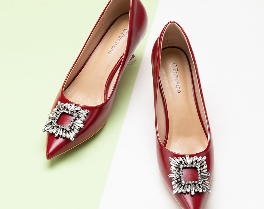 Red leather pumps featuring a dazzling crystal buckle detail.