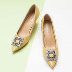 Yellow leather pumps featuring a dazzling crystal buckle detail