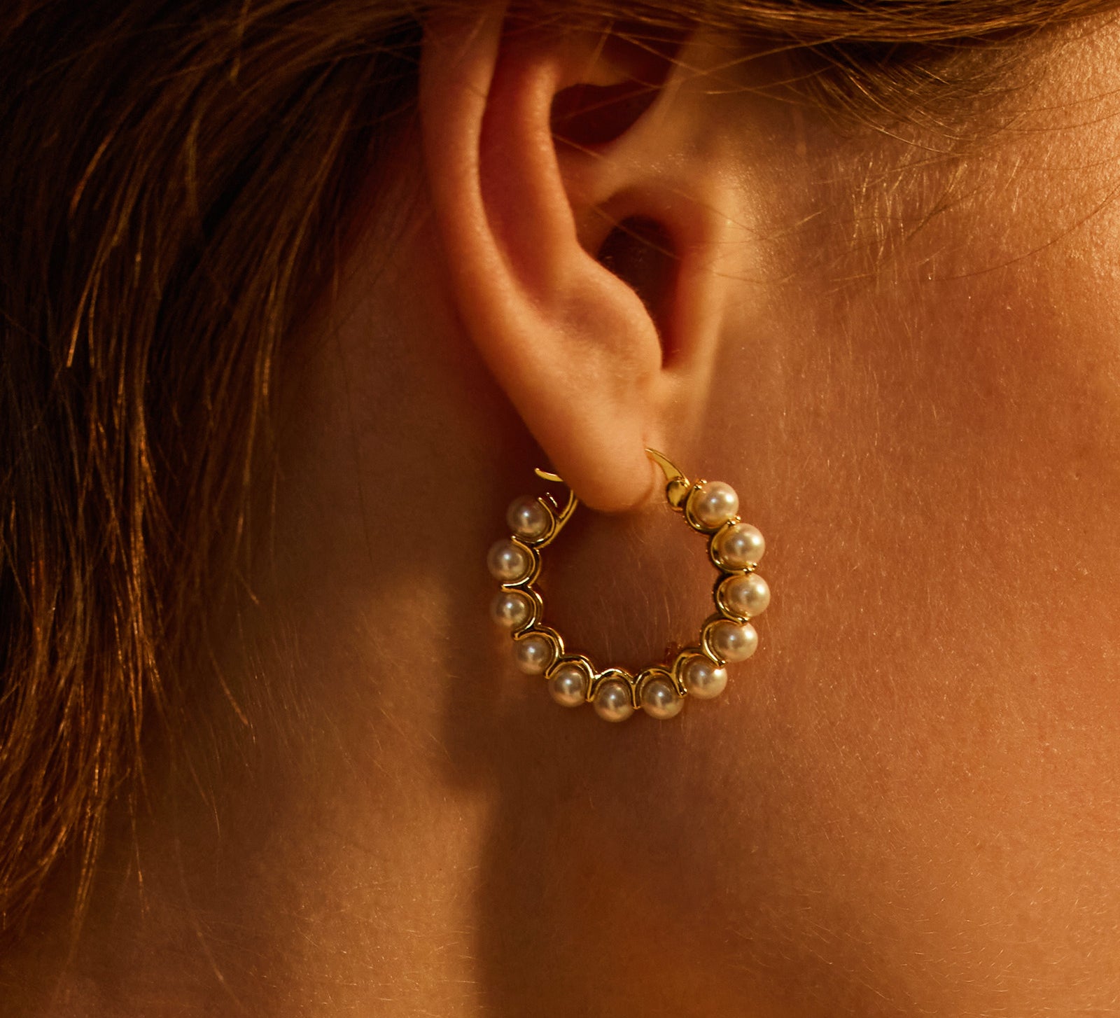  Medium Pearl Huggie Earrings, a classic and timeless design that embraces the ear with medium-sized hoops adorned with lustrous pearls for a touch of sophistication.