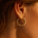  Medium Pearl Huggie Earrings, a classic and timeless design that embraces the ear with medium-sized hoops adorned with lustrous pearls for a touch of sophistication.