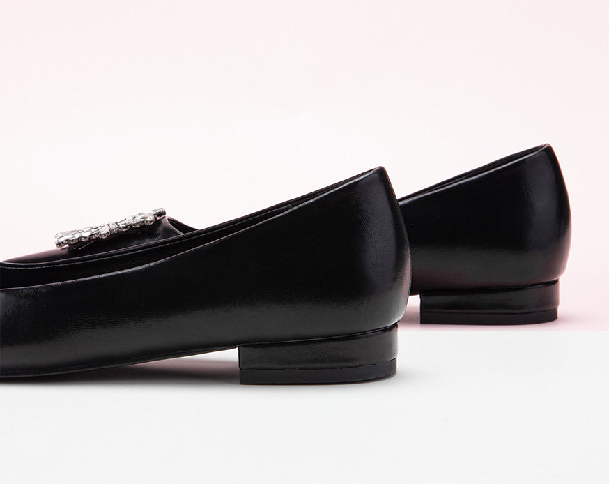 Classic black leather flats adorned with chic decorative details.