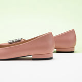 Classic pink leather flats featuring decorative details.