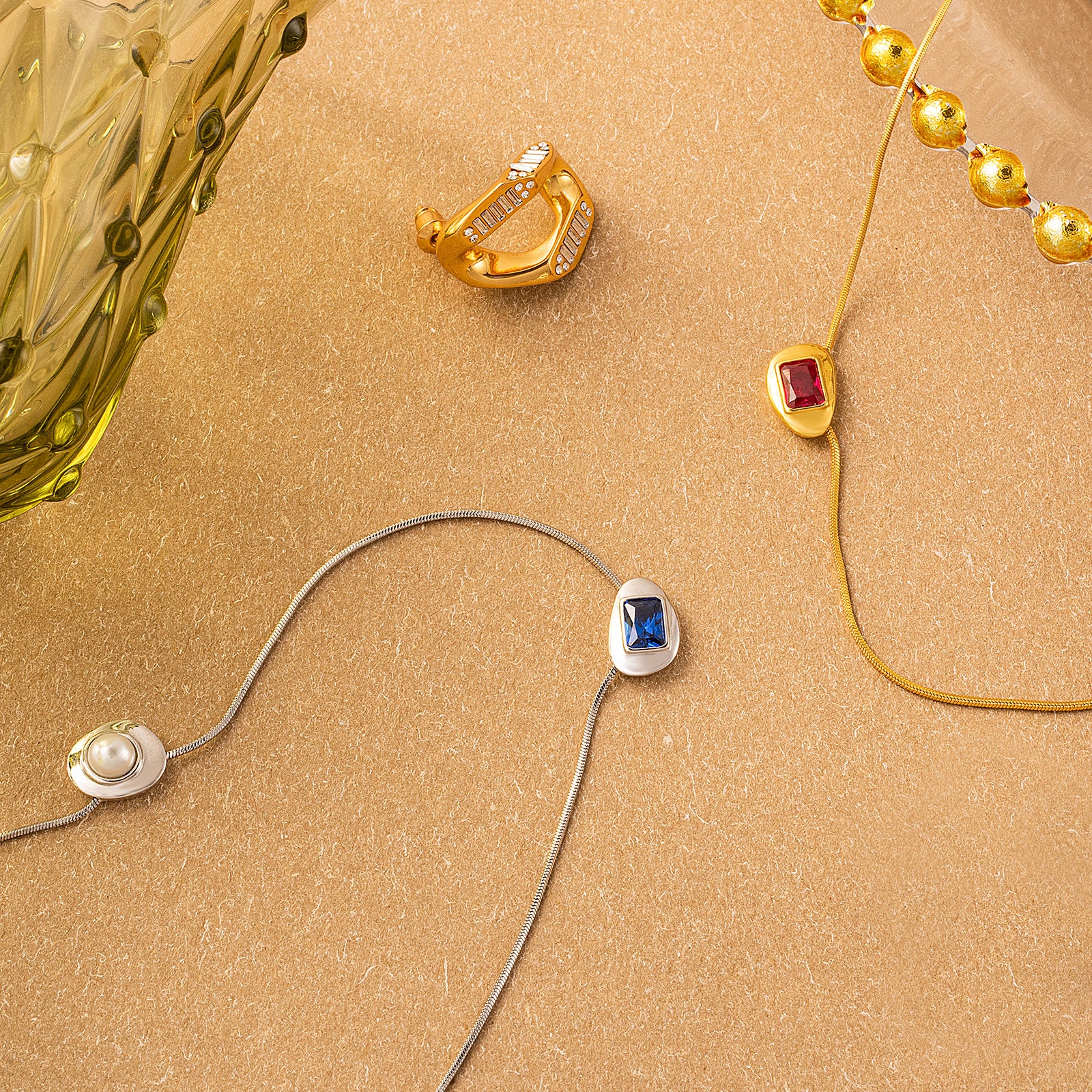 Gold Crystal Drop Necklace, symbolizing eternal beauty, this necklace features a crystal drop pendant in a captivating ruby hue, suspended from a golden chain, expressing a sense of enduring style and grace