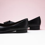 Black point-toe flats in grain leather for a sleek look